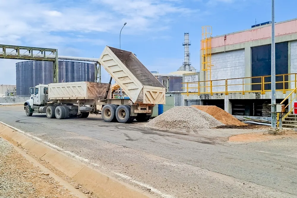 Camión volteo depositando material junto a la nave industrial