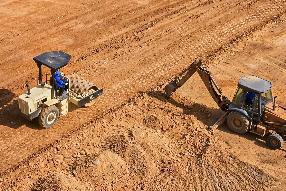 Compactador y excavadora trabajando el terreno
