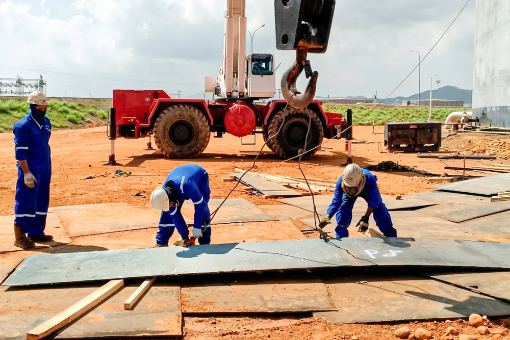 Cuadrilla preparando planchas de acero en el patio con apoyo de grúa